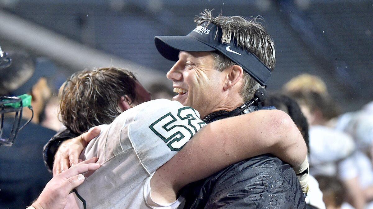 Cardinal Gibbons head football coach Steven Wright embraces Tim Charnot (52) after their victory over Julius Chambers in the NCHSAA 4A Football Championship game. The Cardinal Gibbons Crusaders and the Julius Chambers Cougars met in the NCHSAA 4A Football Championship game in Raleigh, N.C. on December 11, 2021.