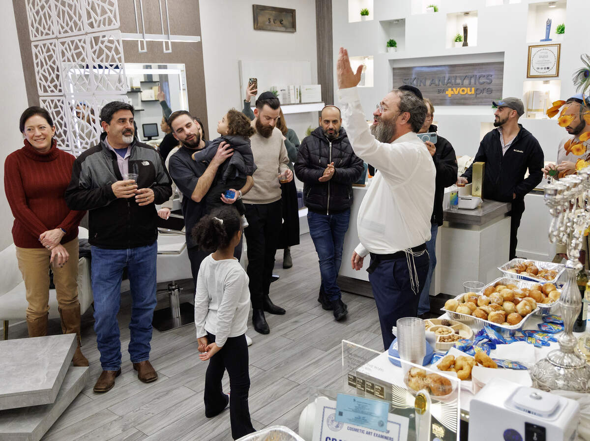 Rabbi Zalman Bluming of Chabad of Durham-Chapel Hill leads a group in song during a gathering at Skin Analytics at The Streets at Southpoint on Thursday, Dec. 18, 2025, in Durham, N.C.