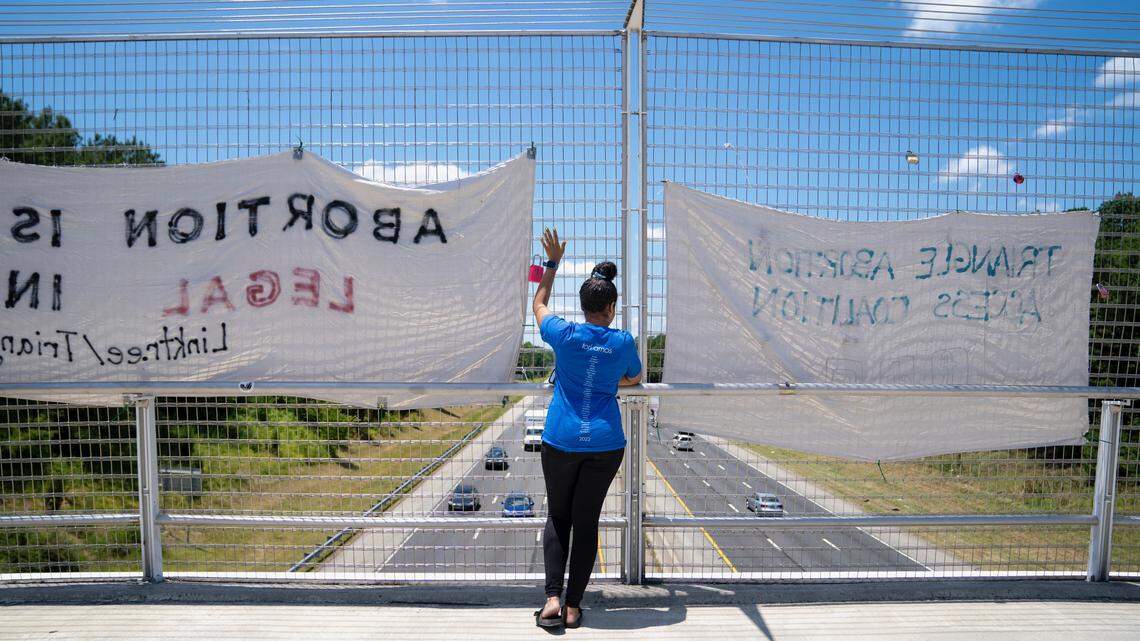 Melissa Jenkins, a volunteer with the Triangle Abortion Access Coalition waves to cars honking at the signs advocating for abortion at the American Tobacco Trail Bridge over I-40 in Durham, N.C. on June 24, 2022 the afternoon that the Supreme Court decision overturning Roe v. Wade was handed down. The volunteers are occupying the bridge throughout the day to let passerbys know abortion in N.C. is still legal despite the court ruling.