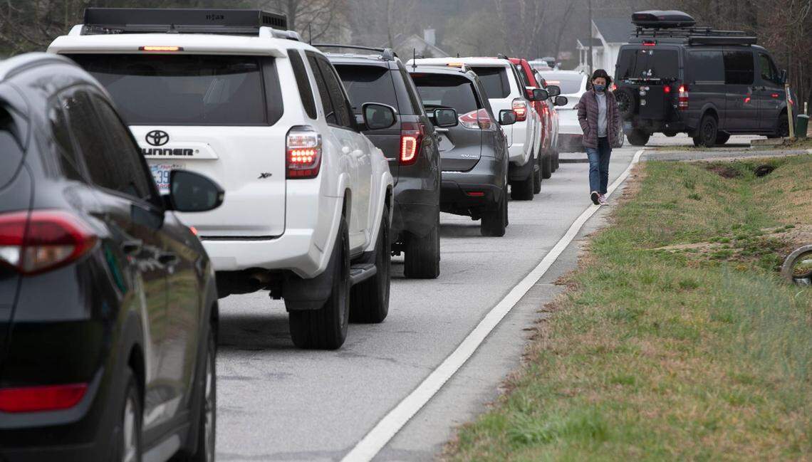 Sarah Newlin walks along Applewhite Road to check out the line to enter Corinth Holders High School for a mass COVID-19 vaccination clinic on Wednesday, March 17, 2021 in Wendell, N.C. The Johnston County Health Department offered the Pfizer vaccine on a first come first served basis between 8:00 a.m.-12:00 noon, or until the supply ran out. Cars lined Applewhite Road for more than a half a mile in both directions waiting to enter the school property. Some arrived as early as 6 a.m. to secure a place in line.
