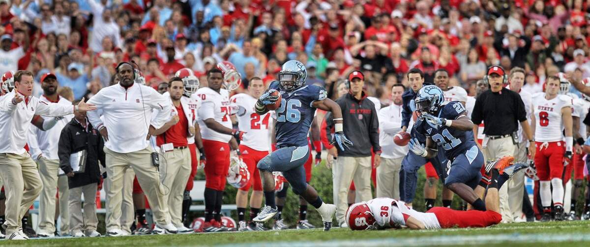 UNC’s Giovani Bernard (26) breaks away from N.C. State’s Will Baumann (36) as he races in front of the Wolfpack bench during a 74-yard punt return to score the game winning touchdown with :13 seconds to play, securing a 43-35 victory over N.C. State on Saturday October 27, 2012 at Kenan Stadium in Chapel Hill, N.C.