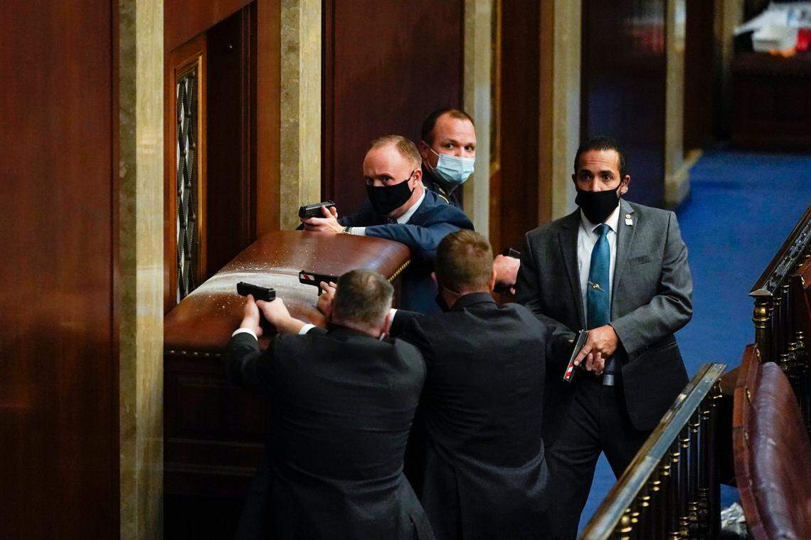 U.S. Capitol Police with guns drawn stand near a barricaded door as protesters try to break into the House Chamber at the U.S. Capitol on Wednesday, Jan. 6, 2021, in Washington. (AP Photo/Andrew Harnik)