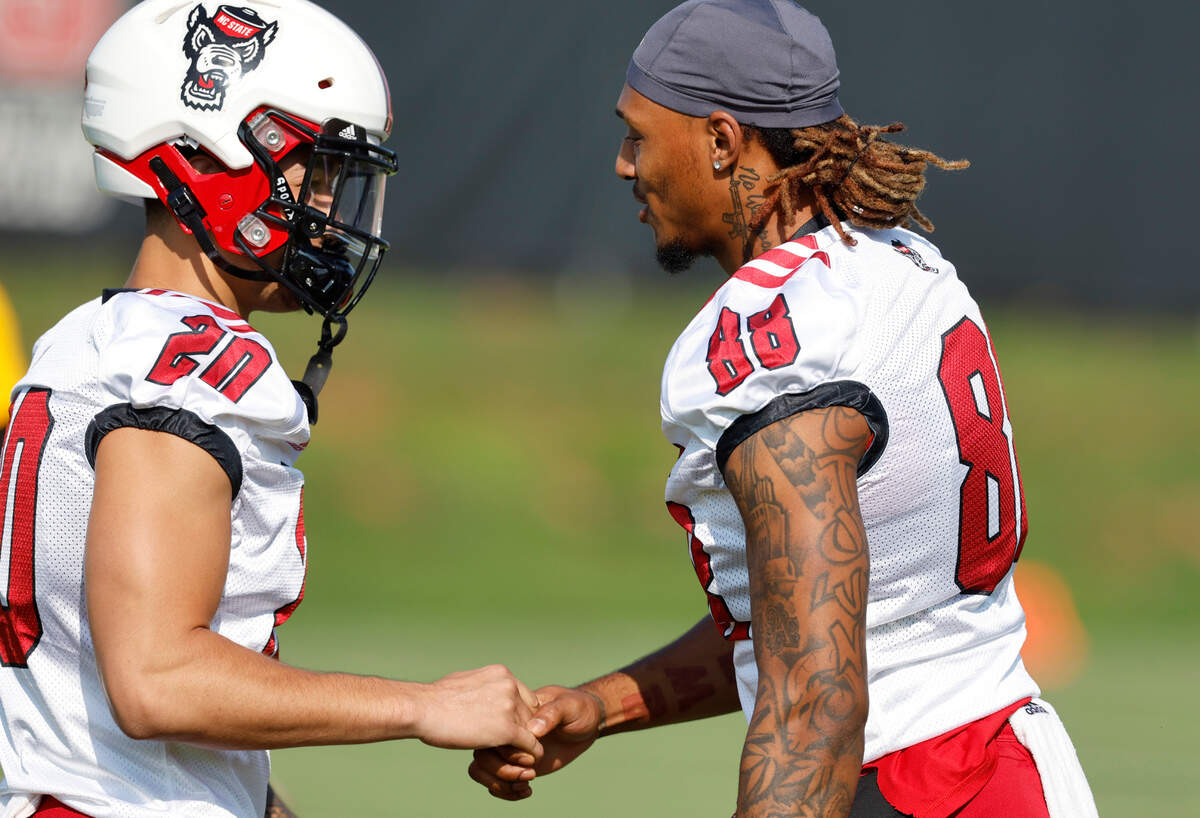 N.C. State’s Devin Carter (88), right, greets Michael Fox (20) at the start of the Wolfpack’s first practice of fall camp in Raleigh, N.C., Wednesday, August 3, 2022.