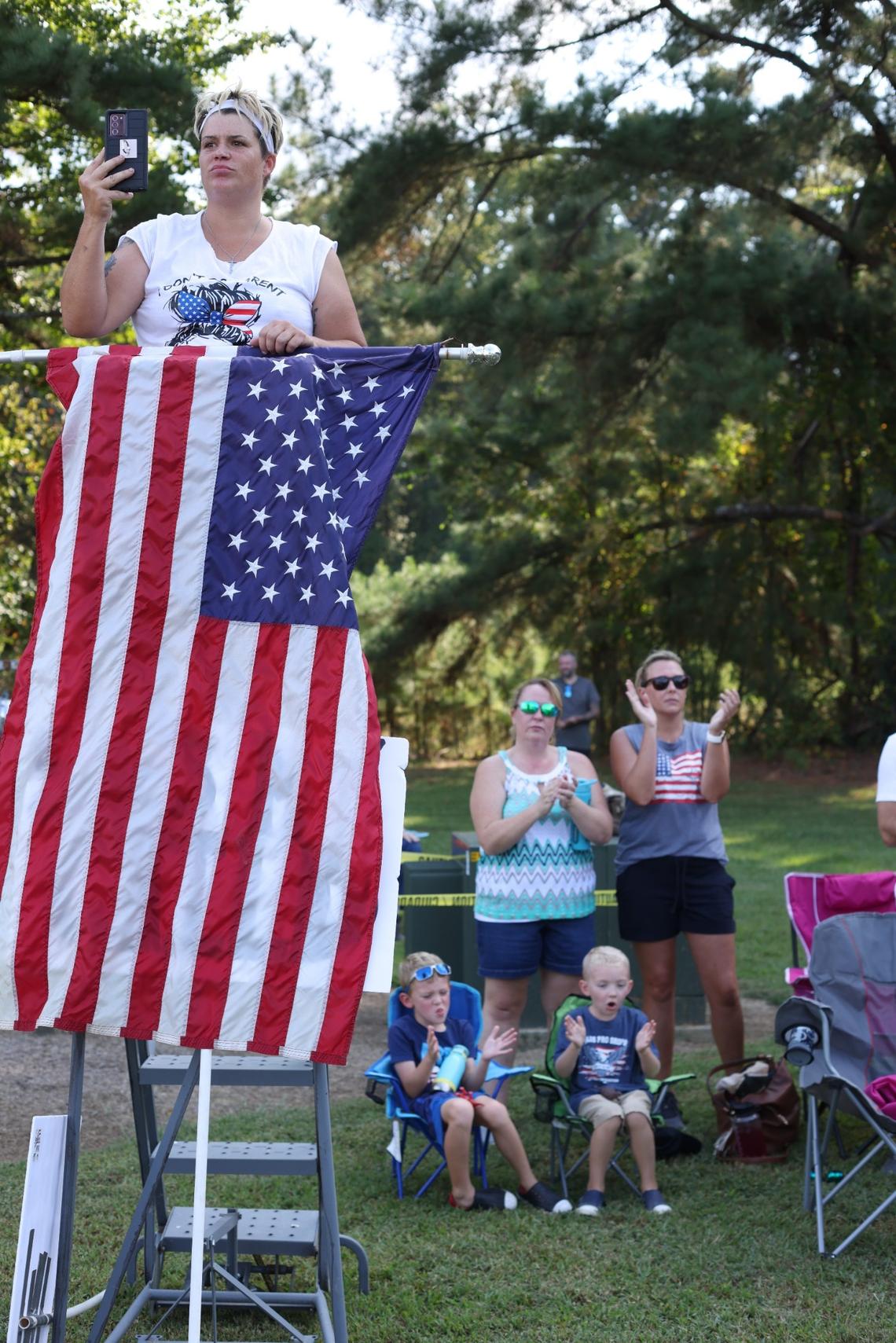 Joanna Davis of Clayton, N.C. uses a step ladder to display her American flag and provide a better view as she watches U.S. Rep. Madison Cawthorn during a rally outside the Johnston County Board of Education meeting on Tuesday, September 14, 2021 in Smithfield, N.C.