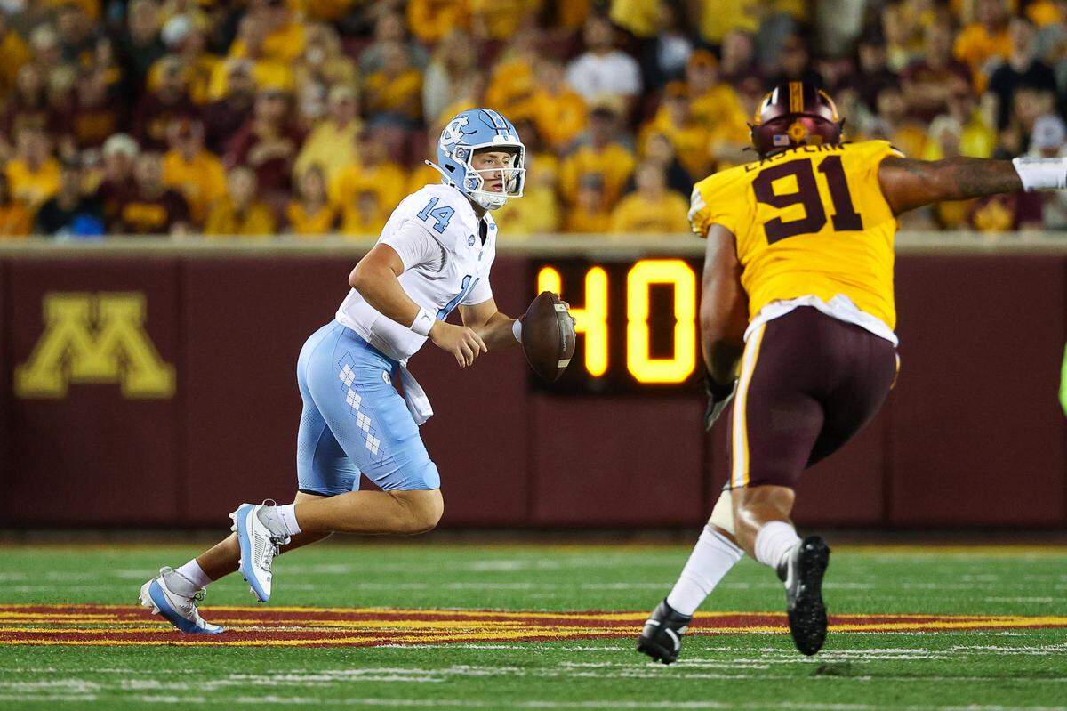 North Carolina Tar Heels quarterback Max Johnson (14) runs the ball as Minnesota Golden Gophers defensive lineman Deven Eastern (91) defends during the first half at Huntington Bank Stadium.