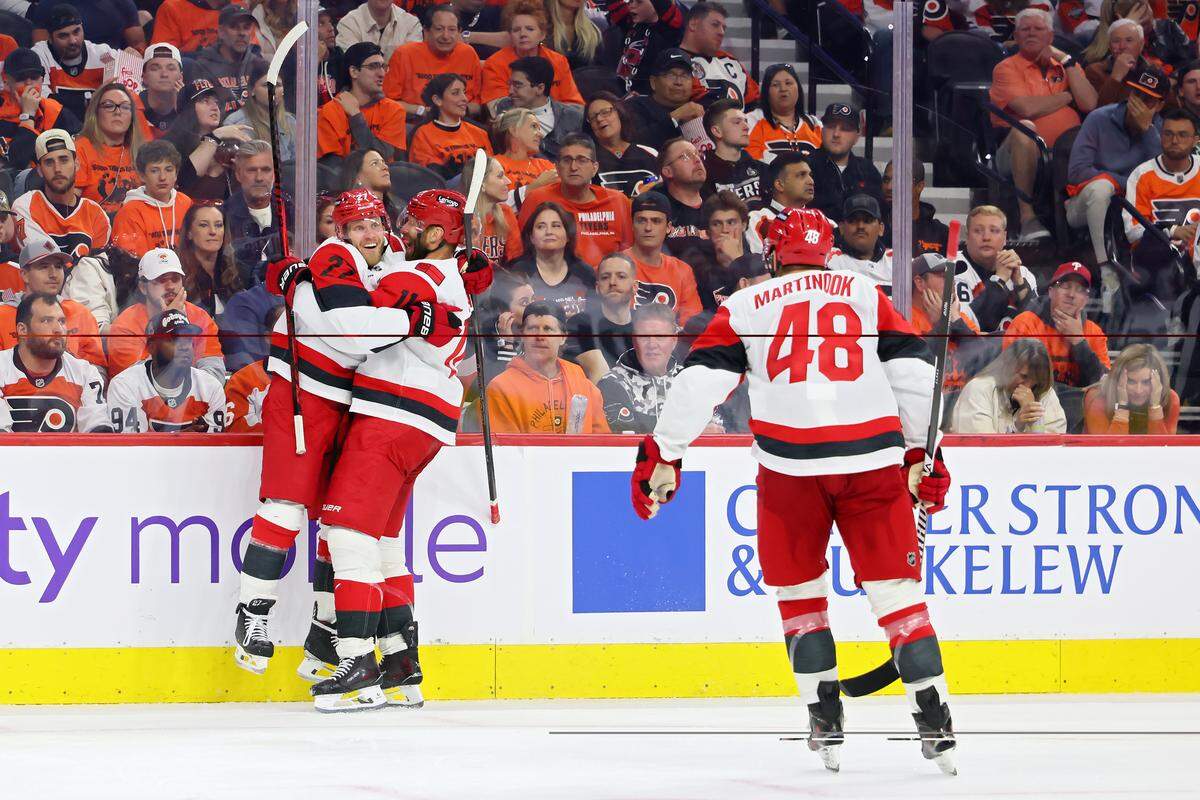 Nikolaj Ehlers (left) and Jordan Staal (center) of the Carolina Hurricanes celebrate a third-period goal against the Philadelphia Flyers as teammate Jordan Martinook skates to join the celebration in Game 3 of their second-round Stanley Cup Playoff series at Xfinity Mobile Arena on May 7, 2026 in Philadelphia, Pennsylvania.