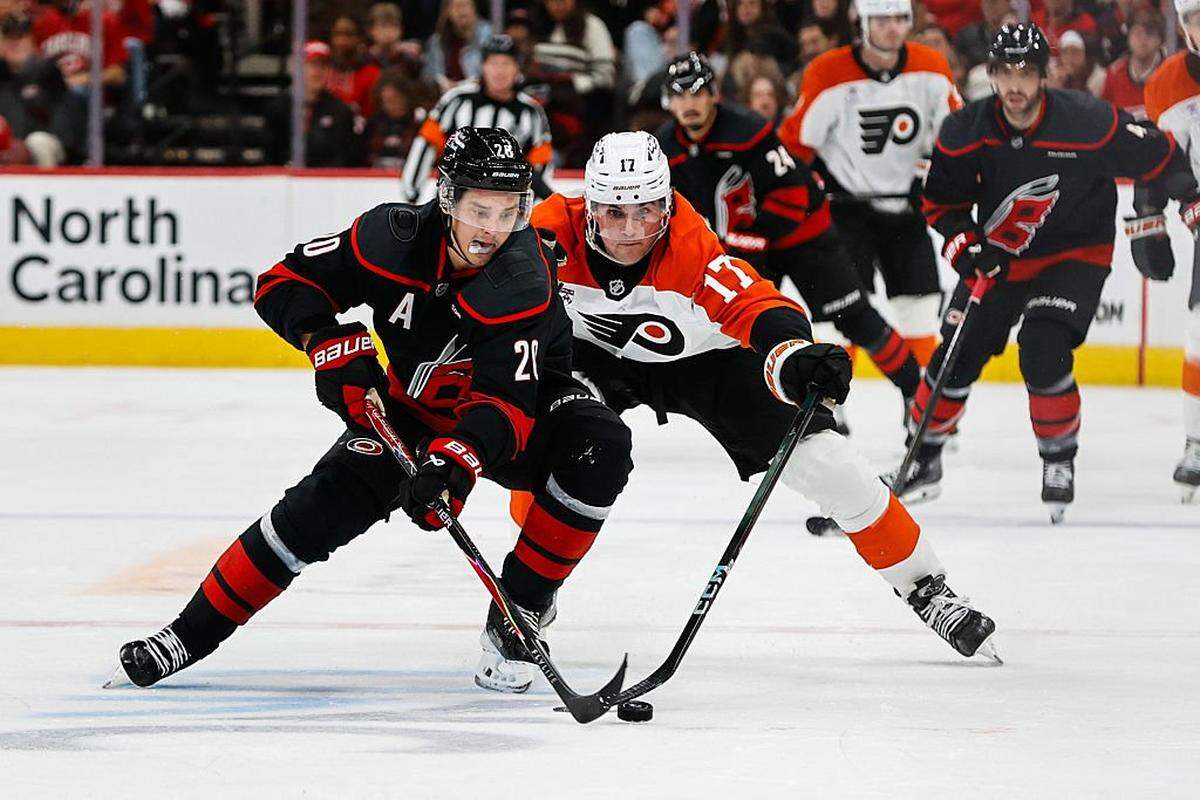 Jett Luchanko (17) of the Philadelphia Flyers and Sebastian Aho of the Carolina Hurricanes vie for the puck during the first period of the game at Lenovo Center on October 11, 2025 in Raleigh, North Carolina.