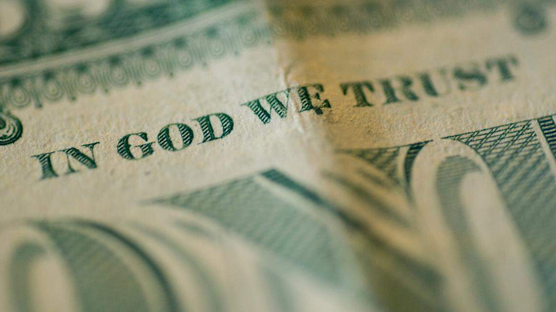 A close up shot of rolled up American bills. Focus on “In God We Trust”