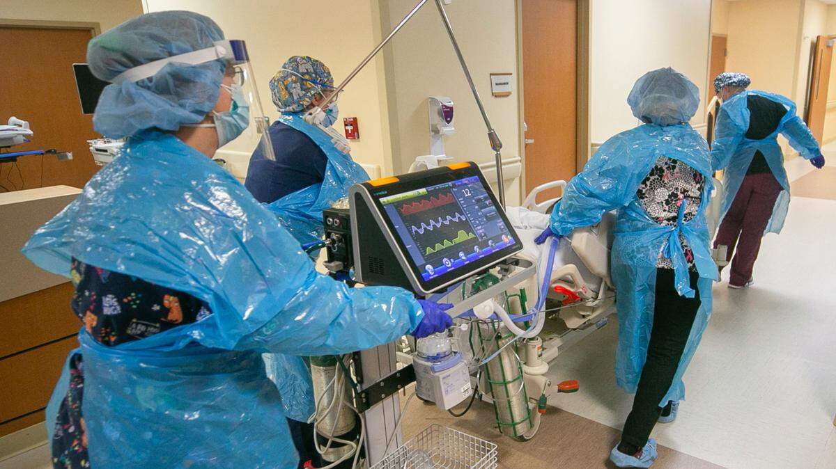 Hospitals across North Carolina are being overwhelmed by the latest COVID-19 surge. Here, a team of nurses and respiratory therapists move a patient into the intensive care unit at Johnston UNC Health Care in Clayton on Aug. 19, 2021. Every bed in the 10-bed unit was filled with COVID patients.