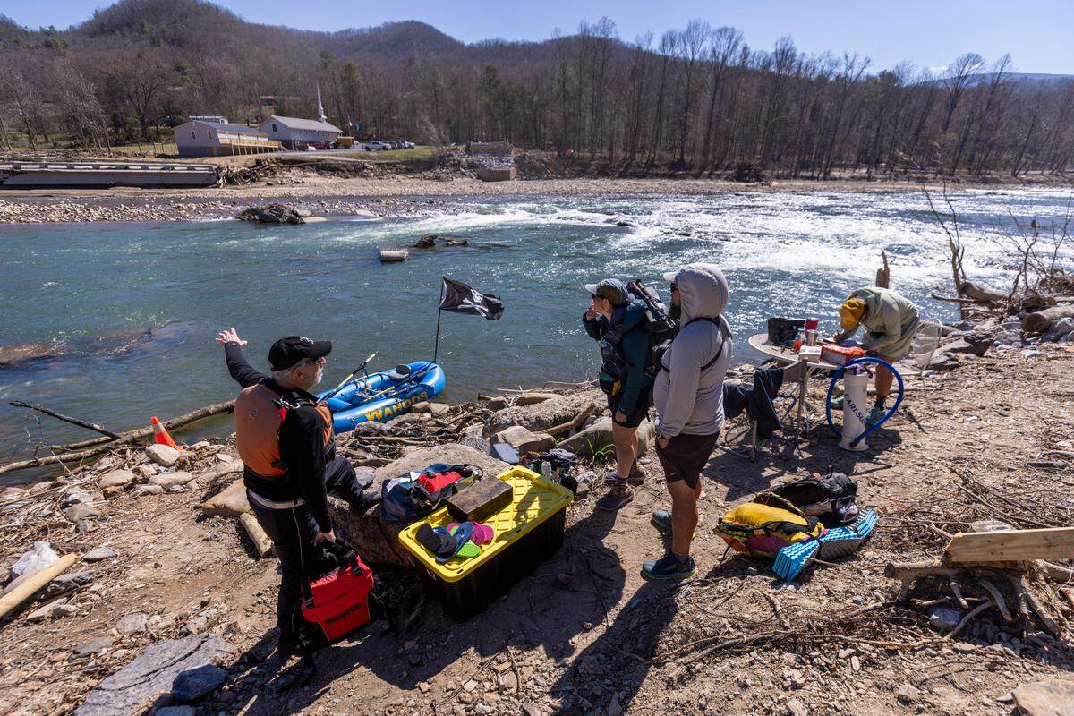 Mike Crooks, left, a rafting guide with Wahoo’s Adventures, prepares to ferry Appalachian Trail hikers across the Nolichucky River near the former site of the Chestoa Pike Bridge. The Appalachian Trail Conservancy is providing a free daily ferry service in place of the bridge, which was destroyed by the remnants of Hurricane Helene.