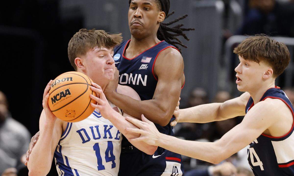 Duke’s Nikolas Khamenia (14) is defended by UConn's Silas Demary Jr. (2) and Braylon Mullins (24) during the first half of Duke’s game against Connecticut in the NCAA Men’s Tournament East Regional Final at Capital One Arena in Washington, D.C., Sunday, March 29, 2026.