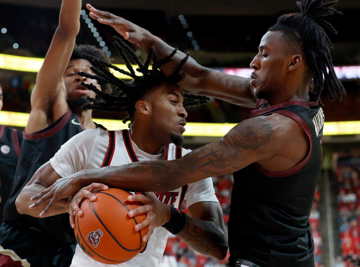 N.C. State’s Jayden Taylor is swarmed by Florida State’s Justin Thomas and Jamir Watkins during the first half of the Wolfpack’s game on Saturday, Dec. 7, 2024, at Lenovo Center in Raleigh, N.C.