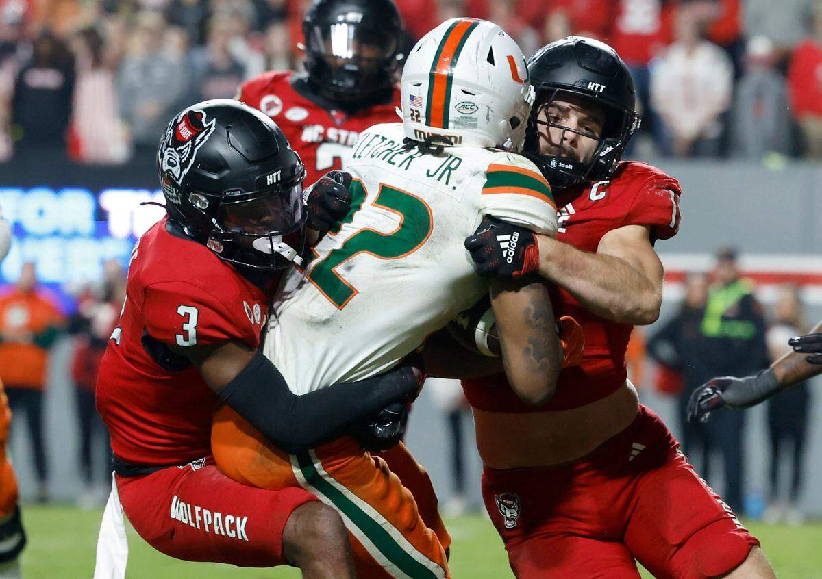 N.C. State’s Payton Wilson (11) and Aydan White (3) tackle Miami’s Mark Fletcher Jr. (22) during the second half of N.C. State’s 20-6 victory over Miami at Carter-Finley Stadium in Raleigh, N.C., Saturday, Nov. 4, 2023.