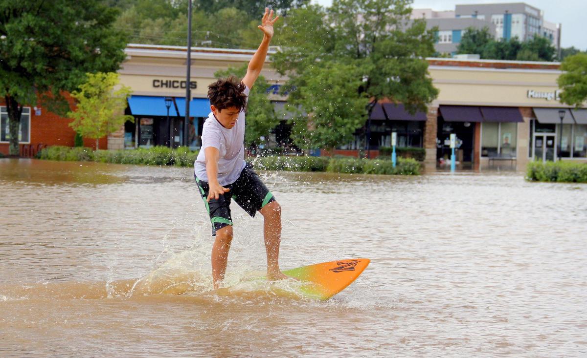 Nicholas Ebel, 12, of Chapel Hill skimboards on the flooded parking lot at Eastgate Crossing shopping center in Chapel Hill on Monday, Sept. 17, 2018.
