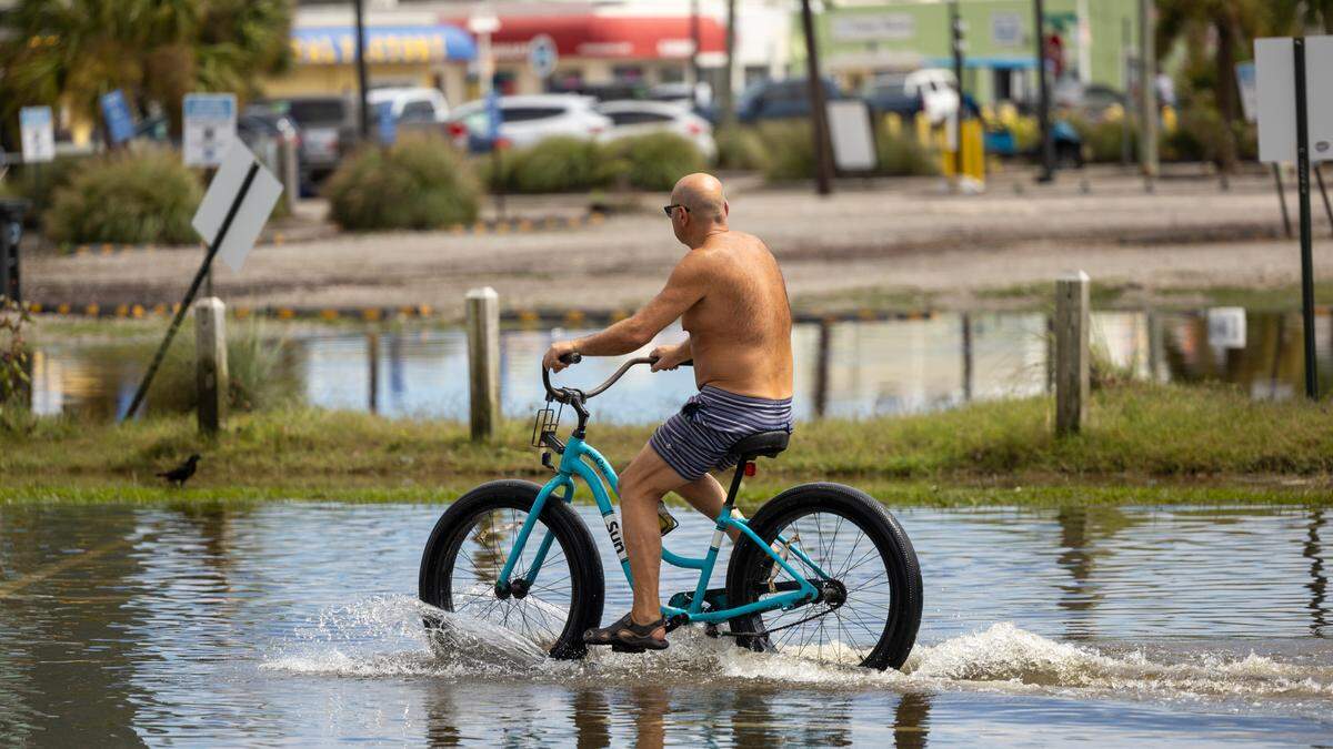 A cyclist pedals through floodwaters as water levels recede in Carolina Beach on Tuesday, Sept. 17, 2024 after an unnamed storm dropped as much as 15 inches of rain in southeastern North Carolina over a 12-hour period. Flood Levels in Carolina Beach rivaled that of Hurricane Floyd in 1999.