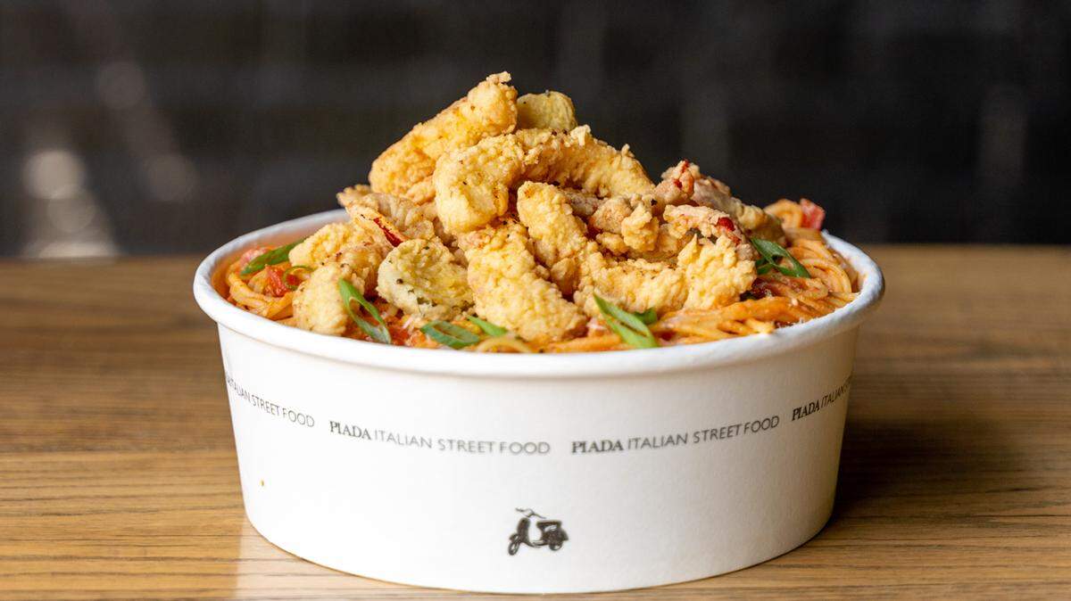 Calamari diavolo pasta from Piada Italian Street Food is made with spicy diavolo sauce, bruschetta tomatoes, chopped green onions, grated parmesan and fried calamari.