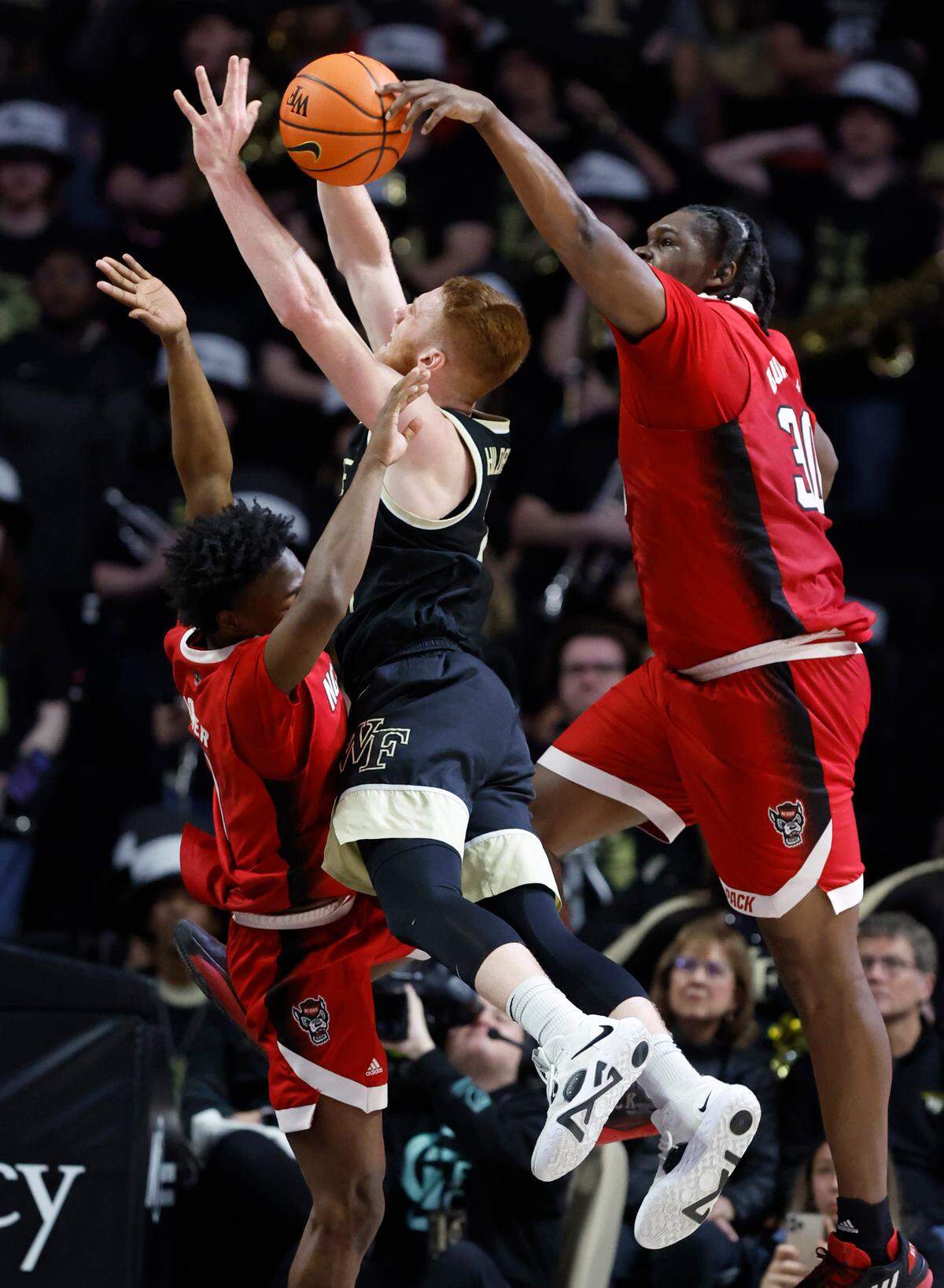 N.C. State’s D.J. Burns Jr. (30) blocks the shot by Wake Forest’s Cameron Hildreth (2) as N.C. State’s Jarkel Joiner (1) also defends late in the first half of N.C. State’s game against Wake Forest at Joel Coliseum in Winston-Salem, N.C., Saturday, Jan. 28, 2023.