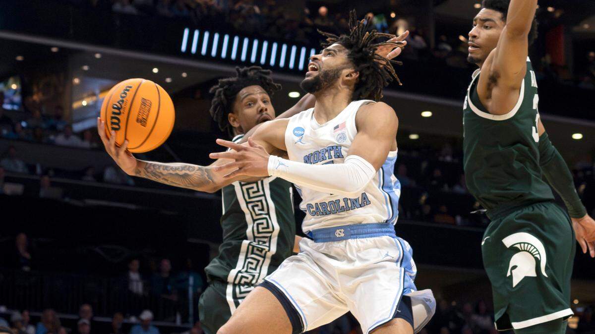 North Carolina’s R.J. Davis (4) drives to the basket against Michigan State’s A.J. Hoggard (11) and Jaden Akins (3) during the second half on Saturday, March 23, 2024, in the second round of the NCAA Tournament at Spectrum Center in Charlotte, N.C. Davis scored 20 pointing lead the Tar Heels to an 85-69 victory.