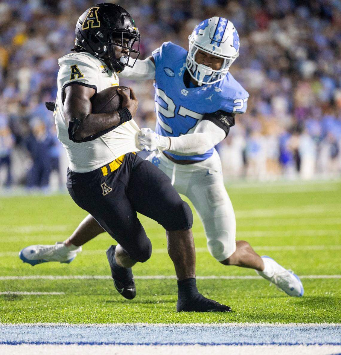 Appalachian State running back Nate Noel (5) scores a touchdown on a 7-yard carry against North Carolina’s Giovanni Biggers (27) to take a 33-27 lead over North Carolina in overtime on Saturday September 9, 2023 at Kenan Stadium in Chapel Hill, N.C. 