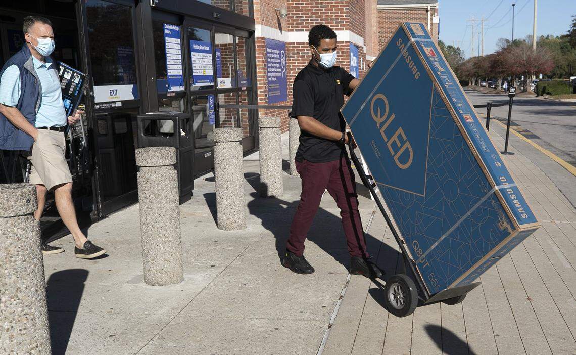Best Buy employee Justin Gregory delivers a 55-inch television to a customer at their curb-side pick-up in Crossroads plaza on Friday, November 20, 2020 in Cary, N.C.