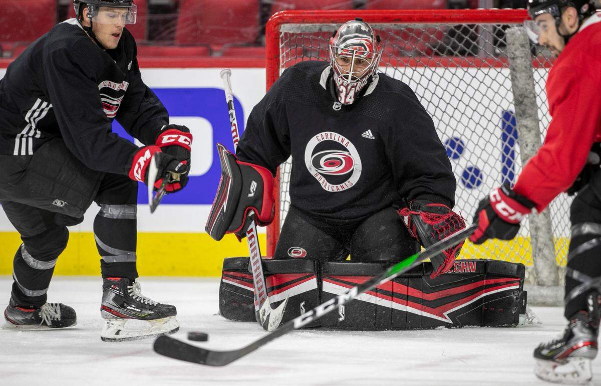 Carolina Hurricanes’ Joey Keane (44), left, and Cedric Paquette (18) work to score on goalie Petr Mrazek (34) during their practice at PNC Arena on Monday, May 24, 2021 in Raleigh, N.C.