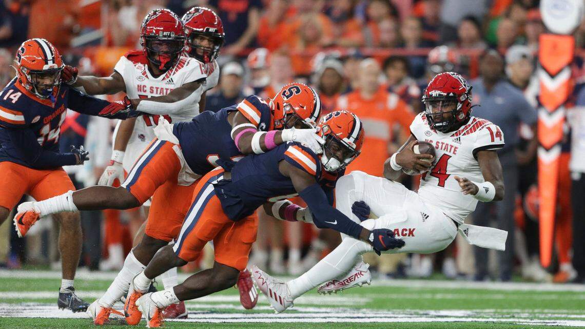 Syracuse defensive back Garrett Williams (8) and linebacker Mikel Jones (3) tackle North Carolina State quarterback Jack Chambers (14) during the first half of an NCAA college football game Saturday, Oct. 15, 2022, in Syracuse, N.Y.