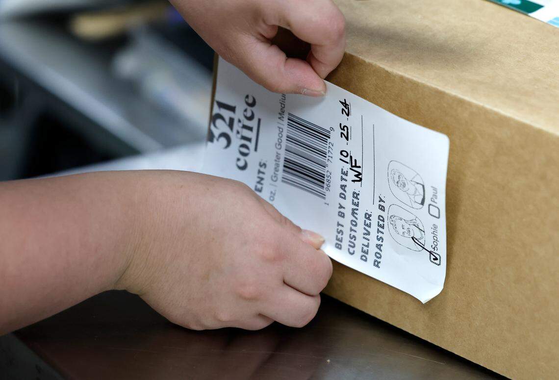 Sophie Pacyna applies a label to coffee that will be delivered to Whole Foods while working at the 321 Coffee roasting facility in Raleigh, N.C., Tuesday, June 25, 2024.