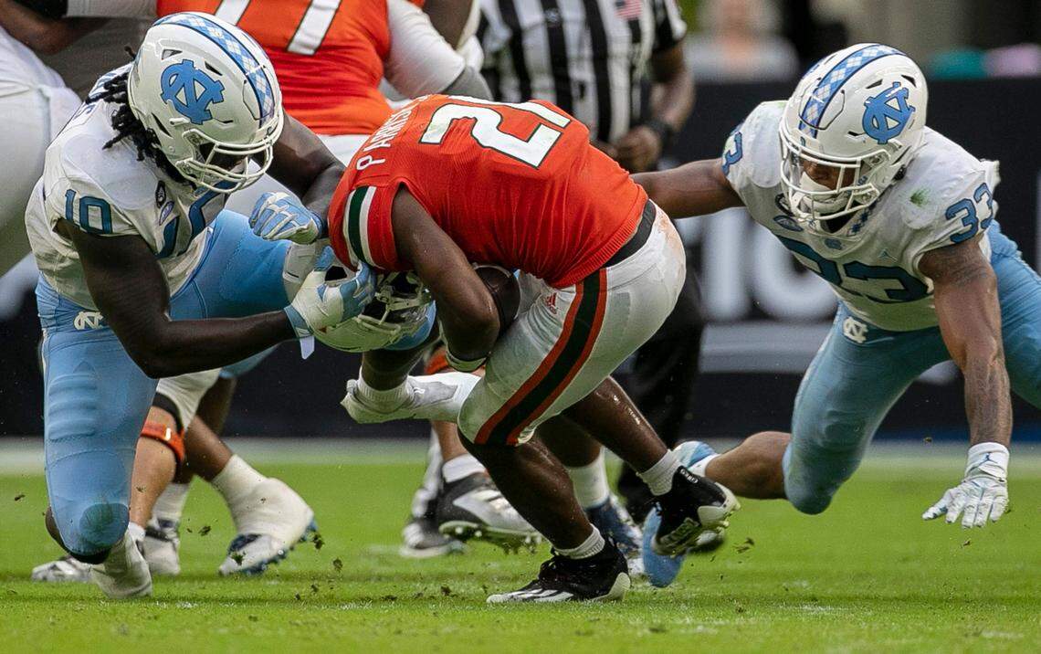 Miami’s Henry Parrish Jr (21) is stopped for a loss by North Carolina’s Desmond Evans (10) and Cedric Gray (33) in the third quarter on Saturday, October 8, 2022 at Hard Rock Stadium in Miami Gardens, Florida.