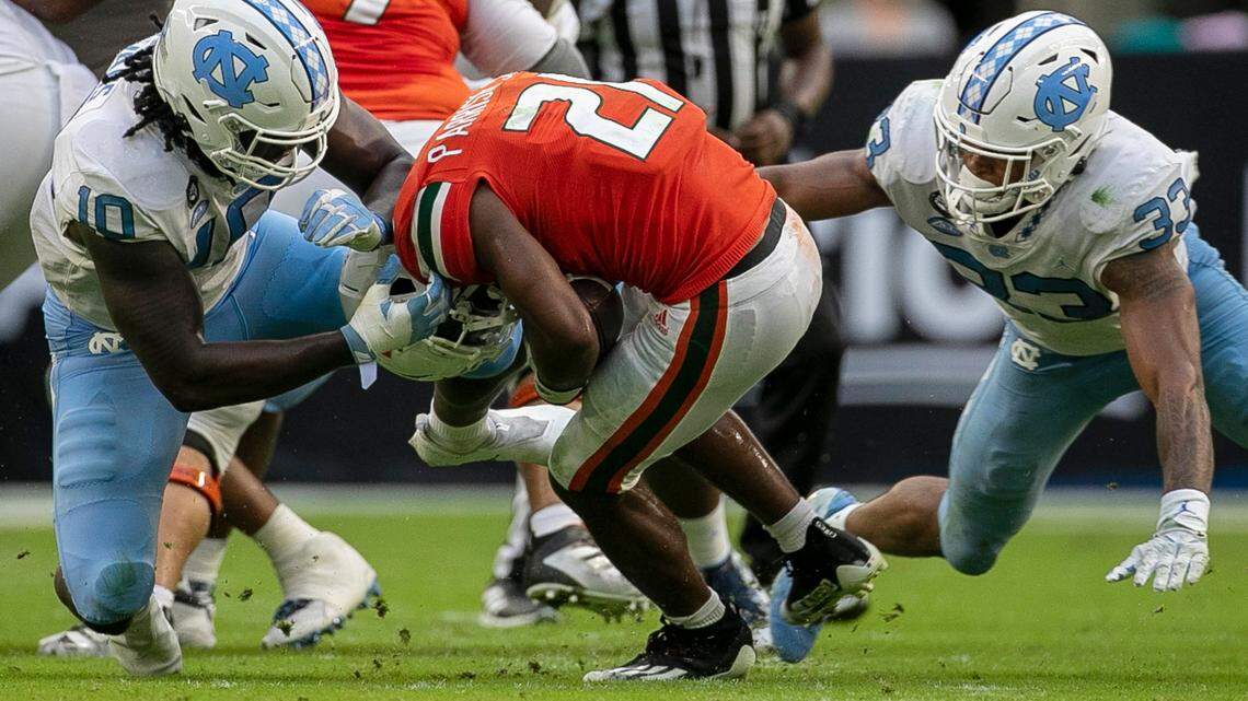 Miami’s Henry Parrish Jr (21) is stopped for a loss by North Carolina’s Desmond Evans (10) and Cedric Gray (33) in the third quarter on Saturday, October 8, 2022 at Hard Rock Stadium in Miami Gardens, Florida.