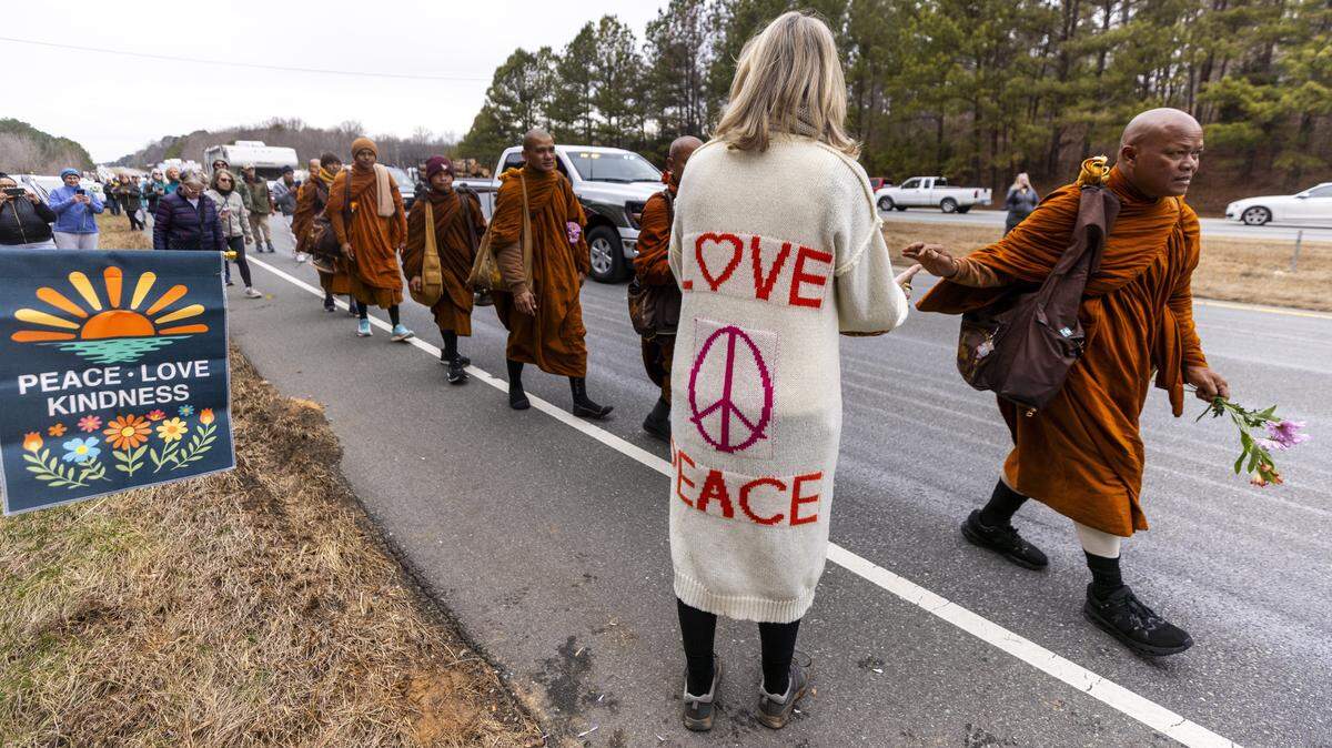 A small procession of Buddhist monks walks along U.S. Highway 64 west of Pittsboro on Thursday, Jan. 22, 2026, as hundreds of onlookers line the highway to welcome them. The monks are making a 2,300-mile pilgrimage from Texas to Washington, D.C., as part of the “Walk for Peace,” an effort to promote peace, compassion and national unity.
