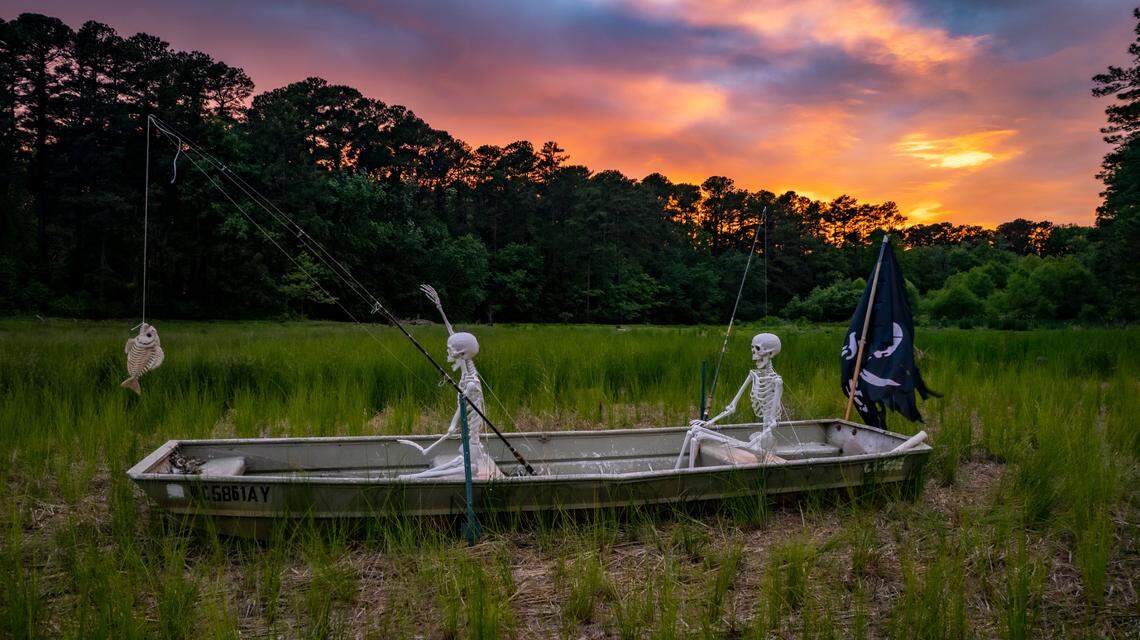 A pair of prop skeletons fish from a jon boat on the former White Oak Lake near the Beltline in West Raleigh. The N.C. Department of Transportation drained the lake last year as part of the effort to widen the Beltline between Wade Avenue and Interstate 40.
