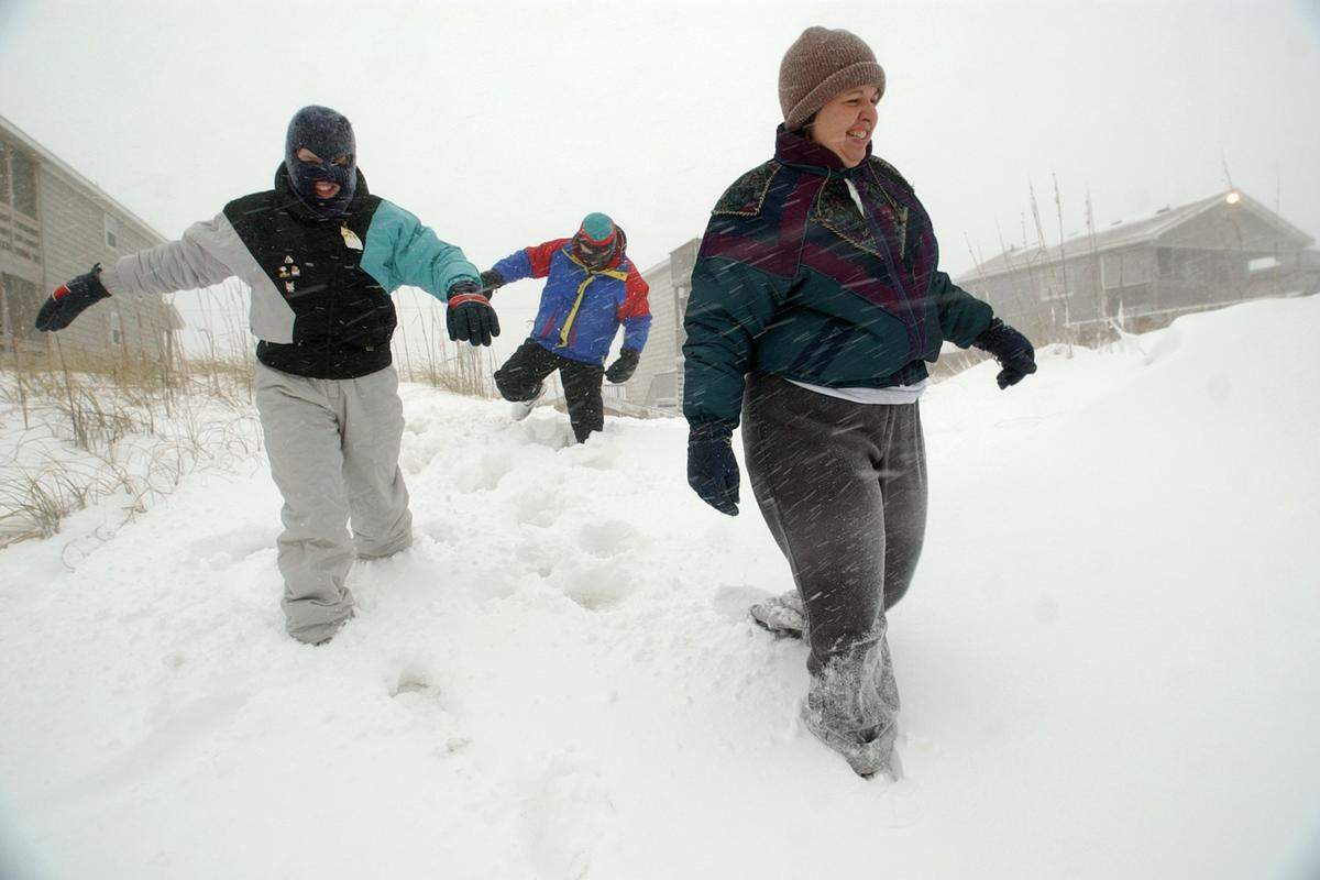 From left Tal Madison, his daughter Ragan Madison, 11, and his wife Julie Madison struggle to walk through knee high snow drifts on the sand dunes overlooking the Atlantic Ocean during a winter storm in January 2002.