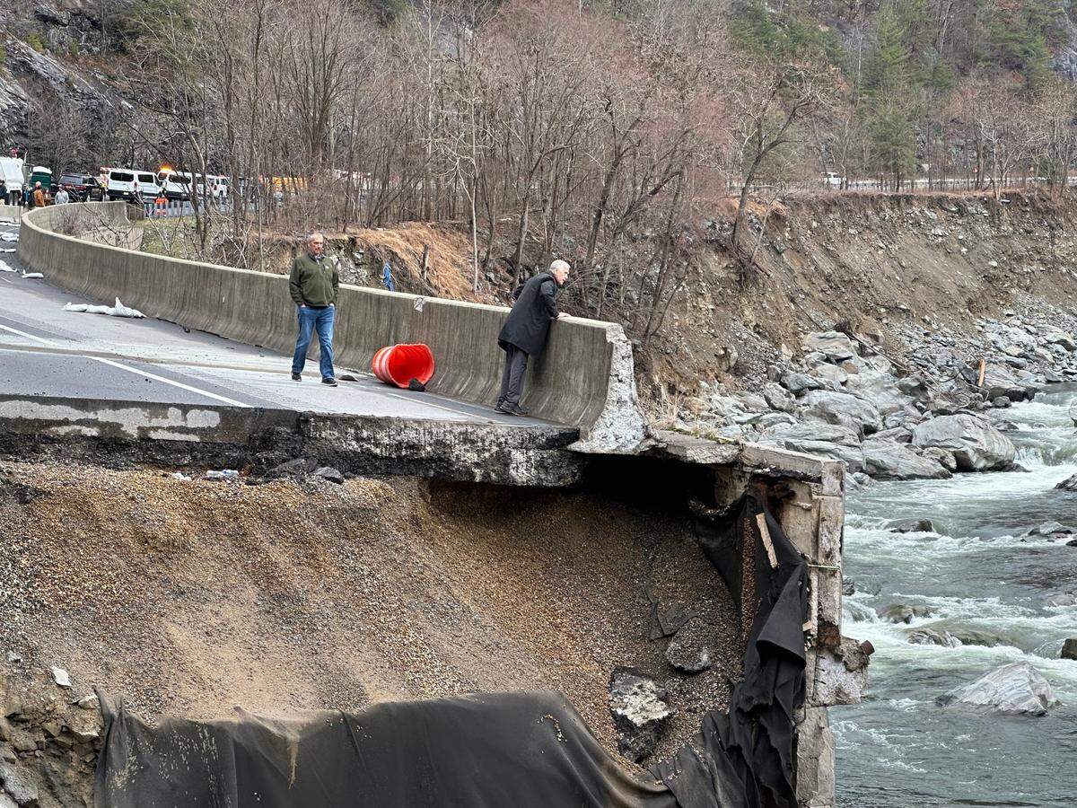 U.S. Sen. Thom Tillis looks into the Pigeon River from what’s left of the eastbound lanes of Interstate 40 on Feb. 10, 2025. Floodwaters from the river washed out more than a mile of the eastbound lanes of I-40 in the Pigeon River Gorge last fall.