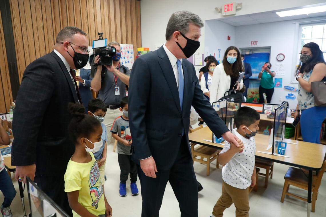 Ibrahim Quadri, right, leads N.C. Gov. Roy Cooper on a tour as Gov. Cooper and U.S. Education Secretary Miguel Cardona, left, tour Bright Beginnings Child Development Center in Cary, N.C., Thursday, May 20, 2021.