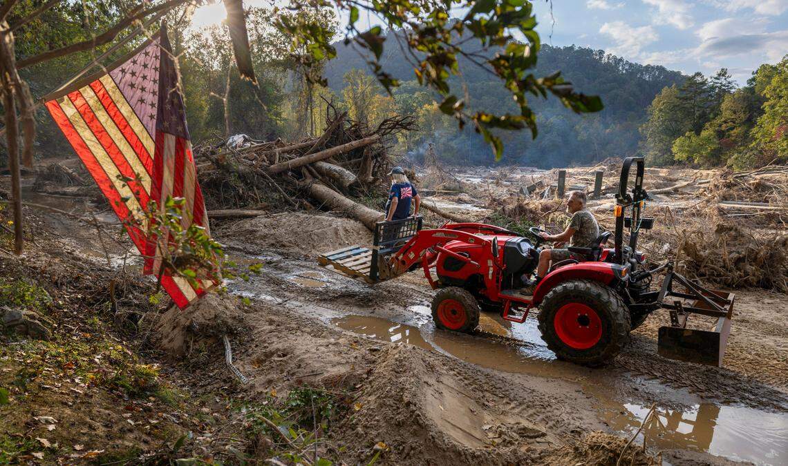 Property owner David Smyrl and his friend Derrick Greene use a tractor to navigate the devastated Green River Cove on Monday, October 7, 2024 near Saluda, N.C. Flooding from Hurricane Helene destroyed numerous homes and the road in the popular white water recreational area.
