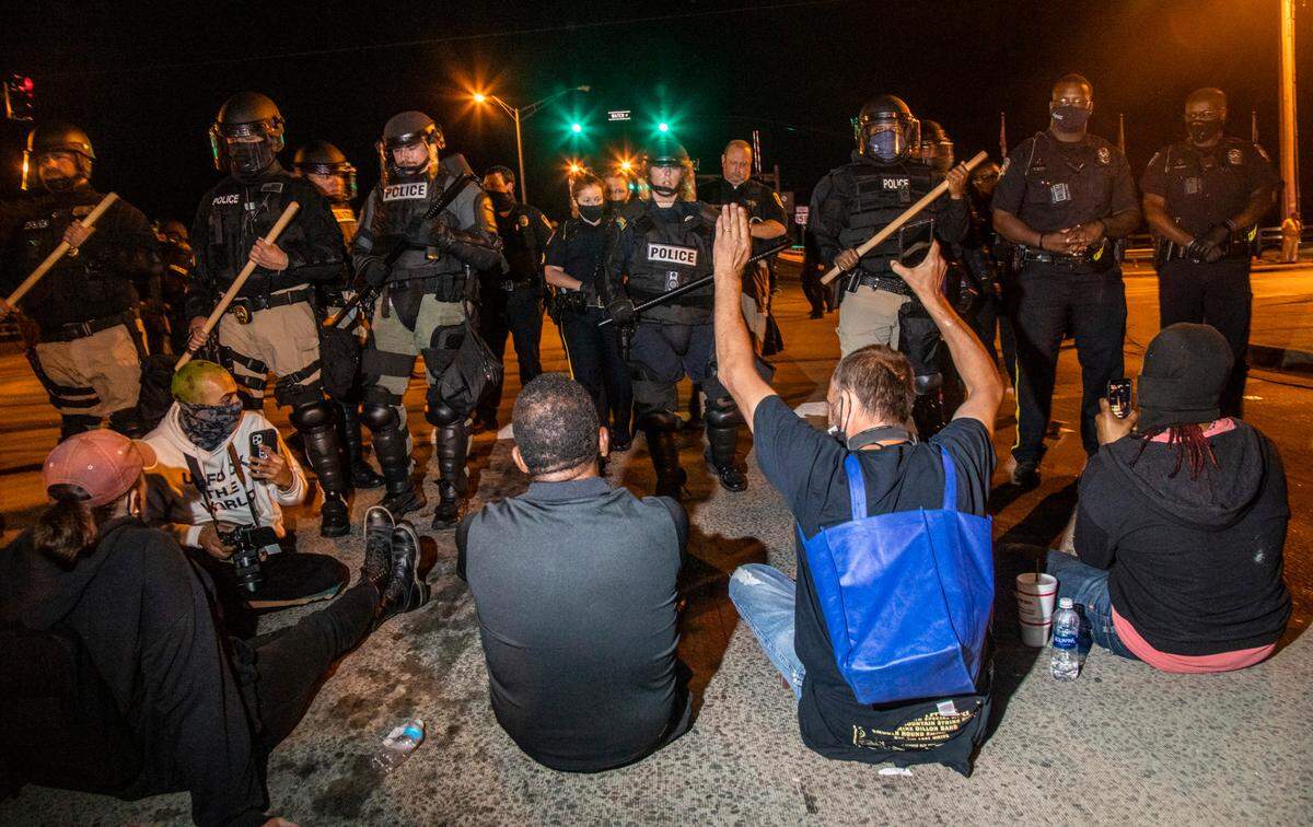 Demonstrators protesting the police killing of Andrew Brown Jr. sit in the street in front of a police line Tuesday, April 27, 2021 in downtown Elizabeth City. At least six protesters were arrested when police in riot gear marched toward roughly a dozen protesters two hours past curfew. Protesters were peaceful but refused to clear the streets.