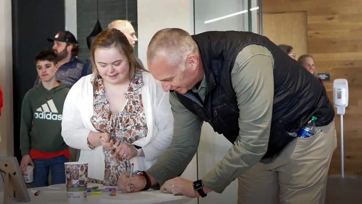 As Sophie Pacyna looks, Dave Doeren signs the guest book at Sam Hening and Sophie Pacyna’s engagement party in February 2024.
