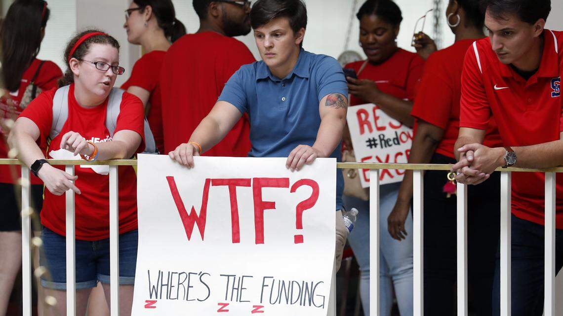 Aaron Haley, a teacher at East Forsyth Middle School holds a sign as thousands of educators and supporters from across the state come to a rally in Raleigh to march to the General Assembly in Raleigh on May 16, 2018.
