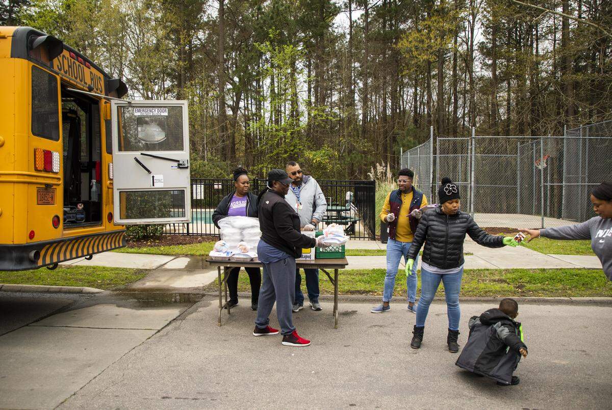 From left, Dena Williams, Linda Brayce, Alex Holmes Jr., La’Paul Wilson, and Latasha Williamson distribute lunch to Kita Beasley, right for her son Ayden Mathis, 3, at one of about 67 meal distribution sites for Durham Public Schools students as all North Carolina public schools remain closed until May 15, 2020, in an effort to slow the spread of the coronavirus, on Thursday, Mar. 26, 2020, in Durham, N.C.