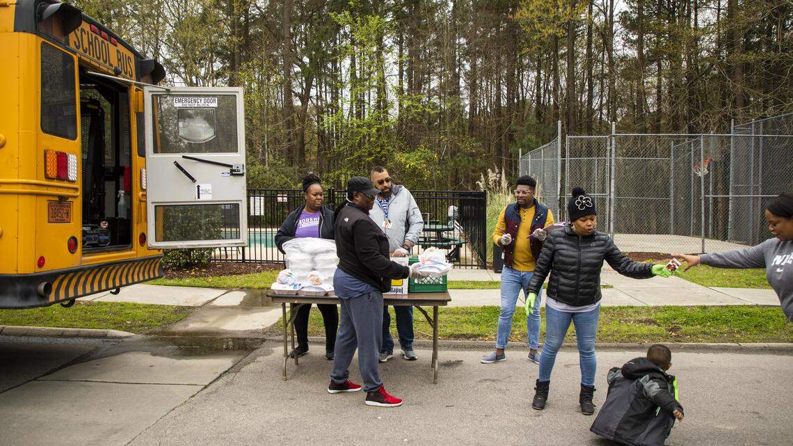 From left, Dena Williams, Linda Brayce, Alex Holmes Jr., La’Paul Wilson, and Latasha Williamson distribute lunch to Kita Beasley, right for her son Ayden Mathis, 3, at one of about 67 meal distribution sites for Durham Public Schools students on Thursday, Mar. 26, 2020, in Durham, N.C.