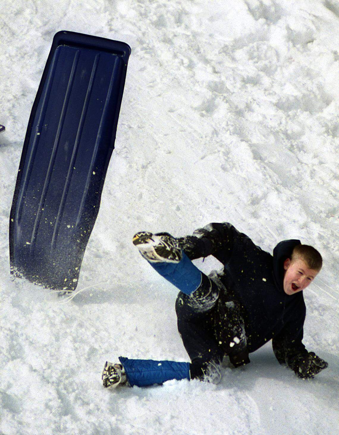 Daniel Coutcher,13, wipes out while riding his snow boat down a steep embankment just off of Cary Parkway in January of 2000.