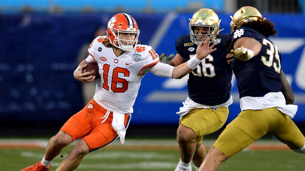 Clemson Tigers quarterback Trevor Lawrence, left, rushes for yardage against the Notre Dame defense during second quarter action at Bank of America Stadium on Saturday, December 19, 2020 in Charlotte, NC. The Clemson Tigers and Notre Dame Fighting Irish faced off in the ACC Championship game.