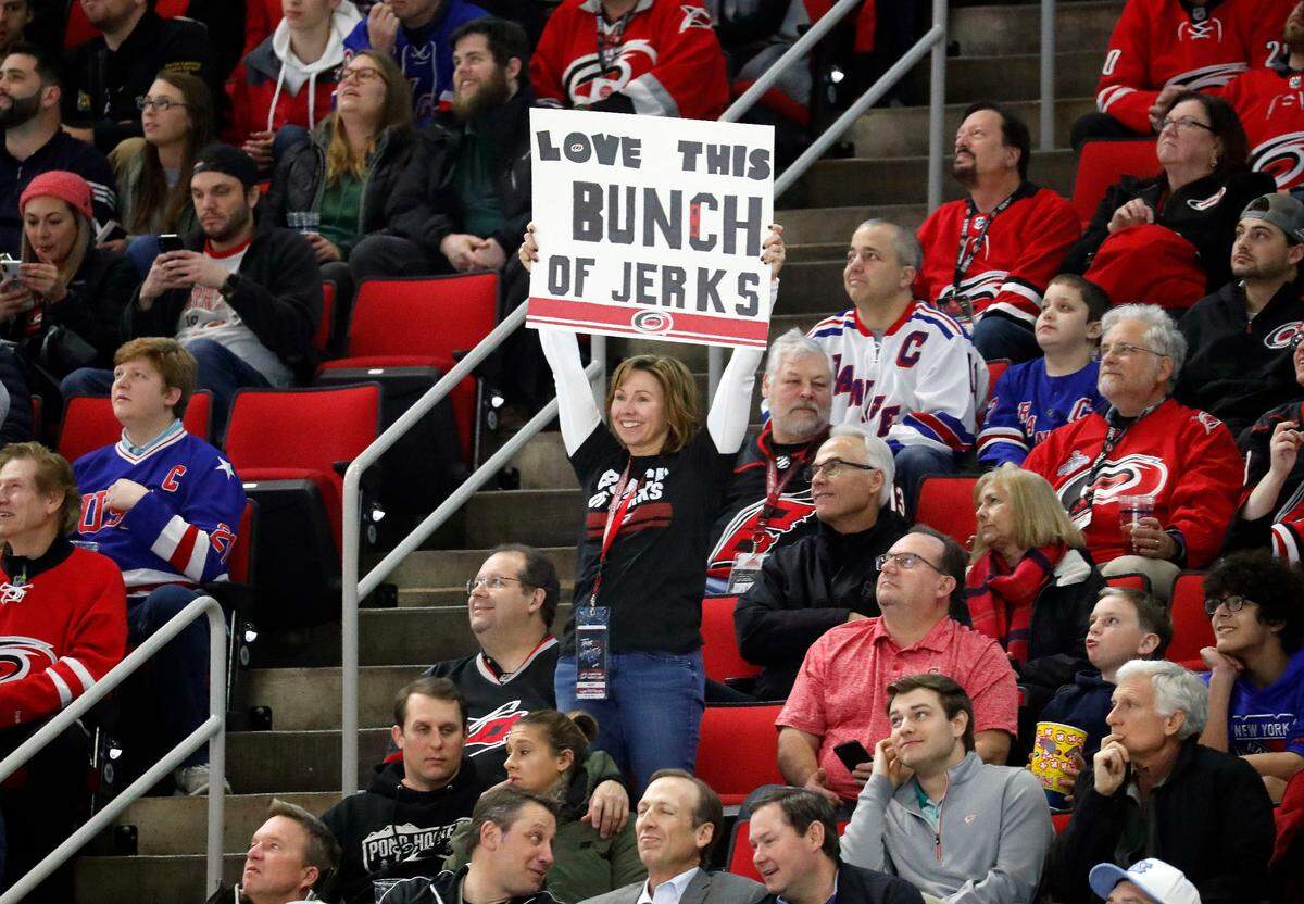 A Carolina Hurricanes fan holds a sign saying she loves this “Bunch of Jerks,” a reference to the team during the second period of an NHL hockey game played against the New York Rangers in Raleigh, N.C., Tuesday, Feb. 19, 2019. Canadian broadcaster Don Cherry said the Hurricanes were a “Bunch of jerks,” for the postgame celebrations that the team does when it wins at home. She also wears a tee shirt expressing the same feelings that the team has recently started selling in response to the comment.