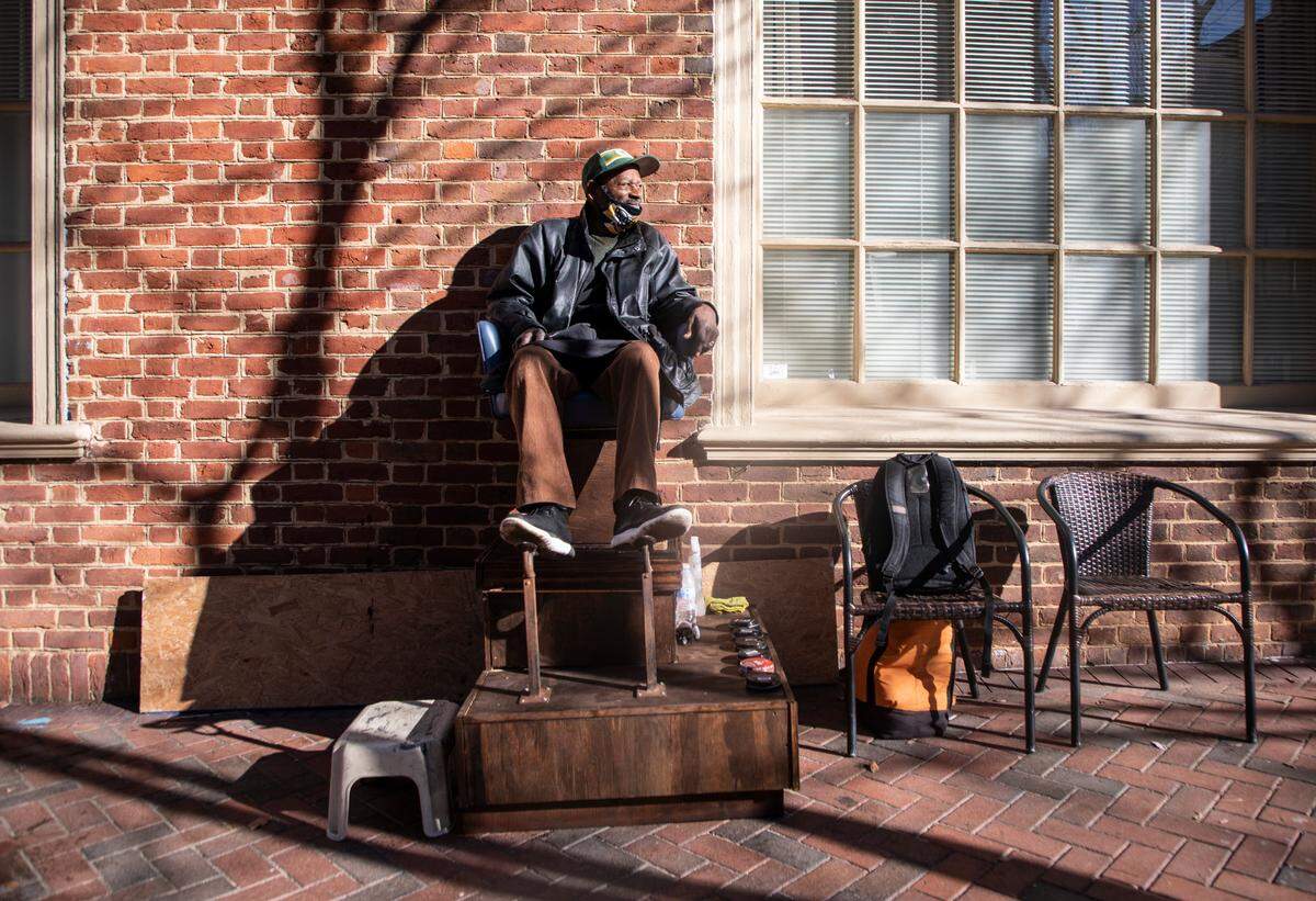 Pierce McKoy, a Durham shoe shiner, sits in his newly refurbished shoe shining chair while waiting for customers on Main Street in downtown Durham, N.C. on Monday, Dec. 13, 2021. A fundraising effort led by a local resident recently raised around $2500 for McKoy’s chair.