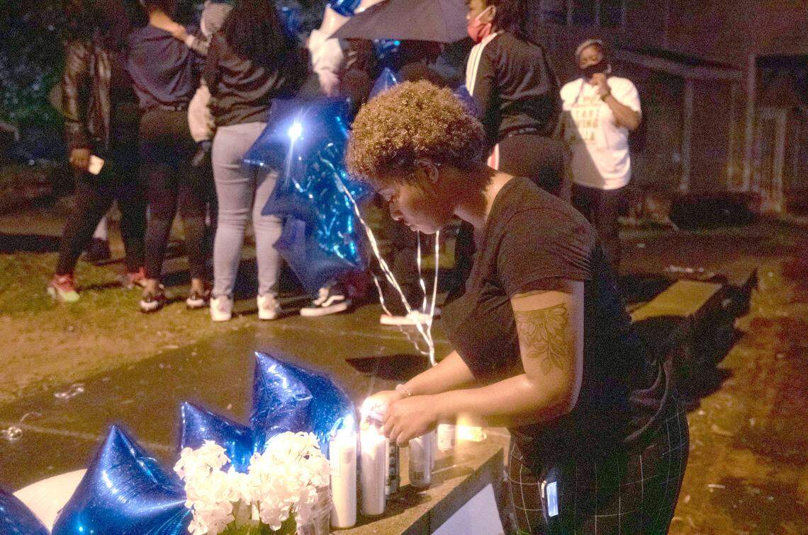 Gicari Davis lights a candle during a balloon release for Anthony Adams, a ninth grader at Southern High School who was shot and killed in downtown Durham Sunday, three blocks from the new police headquarters, on Wednesday, Nov. 11, 2020, in Durham, N.C.