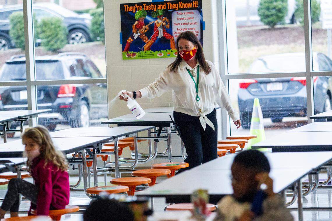 Lisa Brown, principal of Green Elementary School, sanitizes cafeteria tables, March 15, 2021 at the Raleigh school. Monday marked the first day of daily in-person instruction in a year for Wake fourth and fifth-grade students.