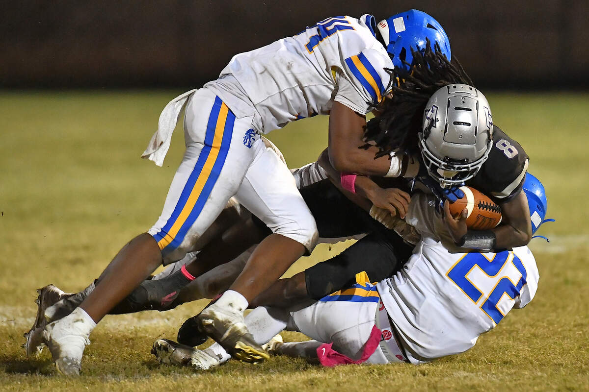 South Garner quarterback Chase Hardy (8) is tackled by Garner's Ja'cori Covington (22) and Levi Archible (24) during the second half. The South Garner Titans and the Garner Trojans met in a conference football game in Raleigh, N.C. October 17, 2025