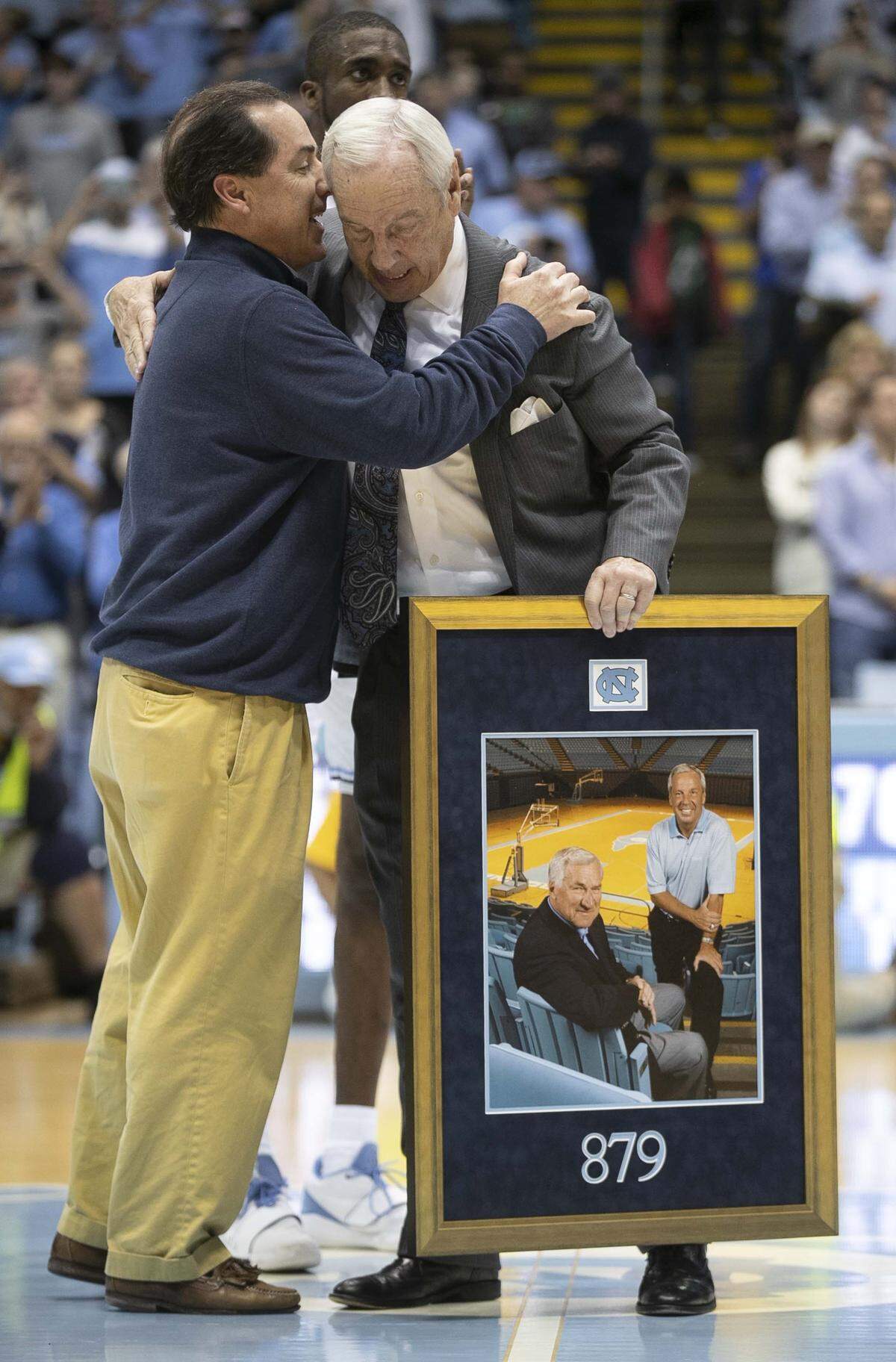 Scott Smith, the son of Dean Smith, embraces North Carolina coach Roy Williams after Williams was honored for tying Dean Smith’s record of 879 career victories following the Tar Heel’s 70-67 victory over Yale on Monday, December 30, 2019 at the Smith Center in Chapel Hill, N.C.