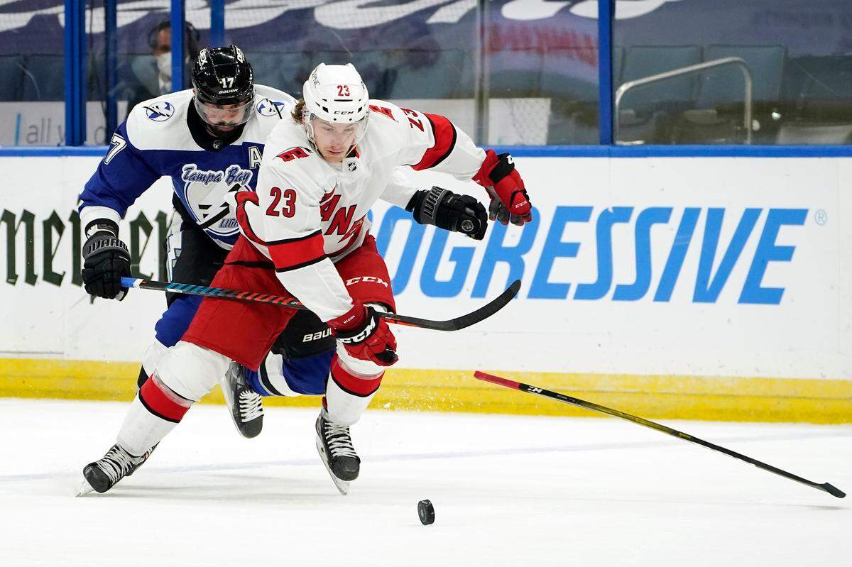 Tampa Bay Lightning left wing Alex Killorn (17) slashes the stick away from Carolina Hurricanes left wing Brock McGinn (23) during the first period of an NHL hockey game Thursday, Feb. 25, 2021, in Tampa, Fla. Killorn was called for the penalty. (AP Photo/Chris O’Meara)
