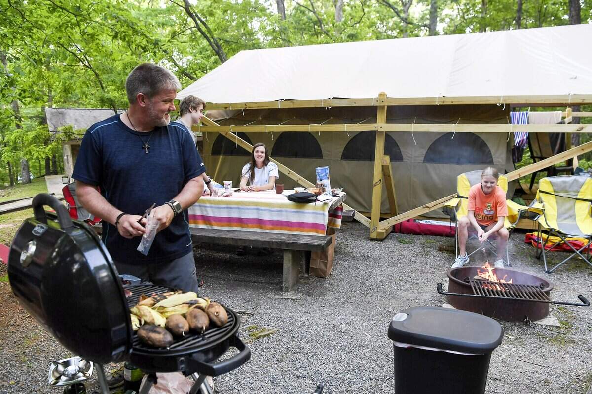 Tommy Halcom grills dinner for his family at their glamping campsite at Lake Powhatan, N.C. These deluxe campsites are designed for families, friends and couples who prefer to enjoy nature and outdoor recreation without sacrificing all the comforts and luxuries of home.